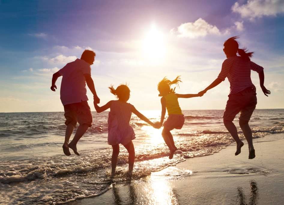 famille sautant sur la plage au coucher de soleil