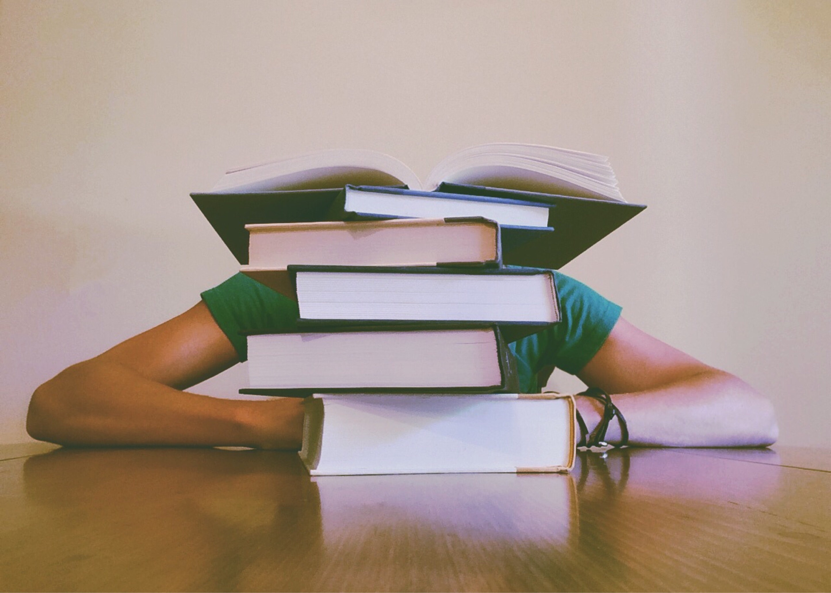 des livres sur une table devant cachant un étudiant