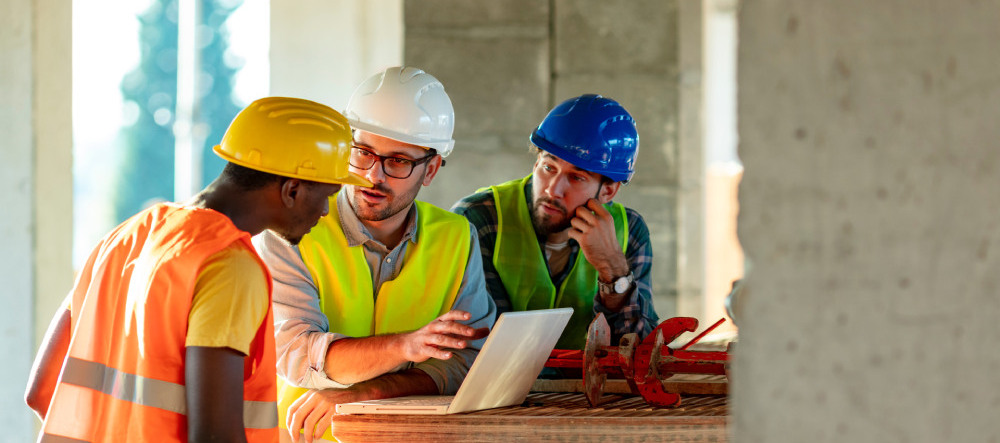 un chargé d'affaires en discussion avec deux ouvriers sur un chantier