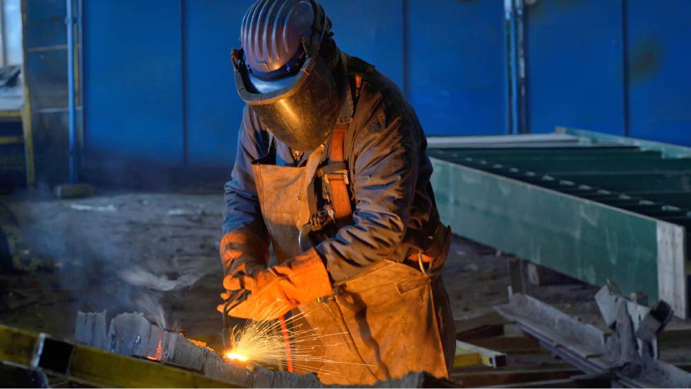 un chaudronnier avec son masque et ses gants de protection en pleine action