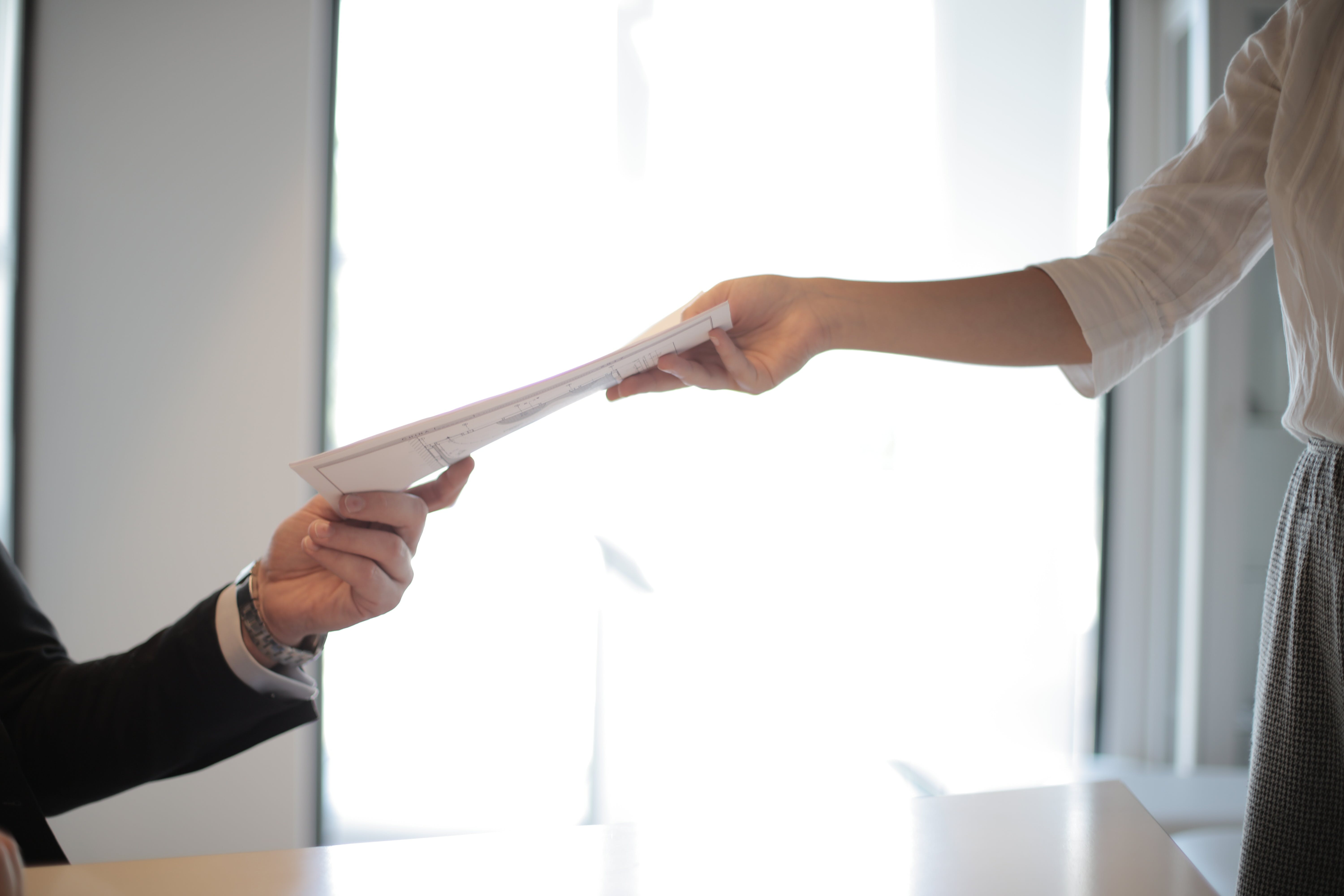 deux mains qui tiennent un document tendu par l'une des deux personnes