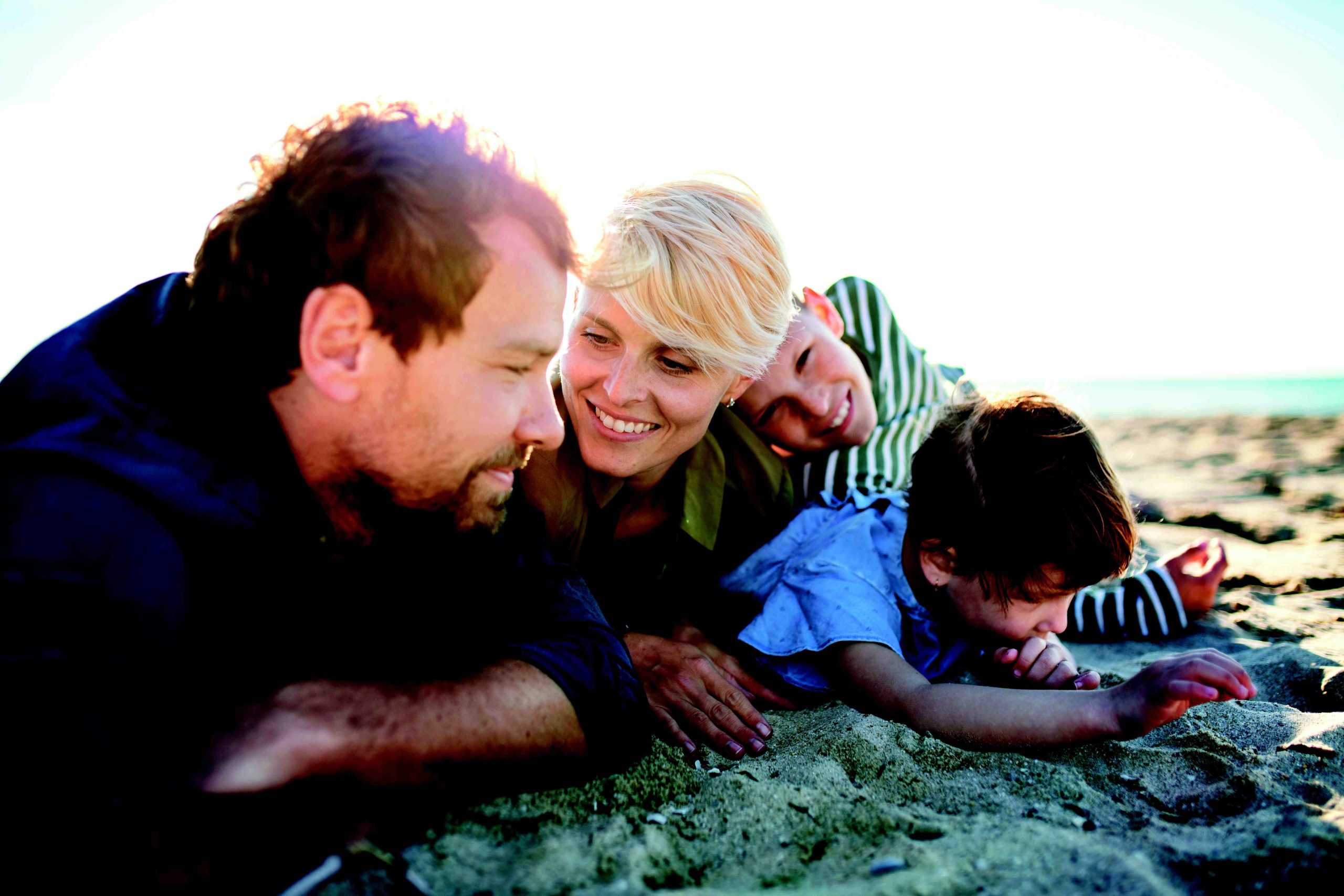 Famille souriante allongée dans le sable